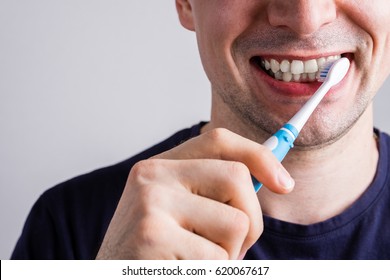 Man Cleaning Teeth With Electric Toothbrush Closeup