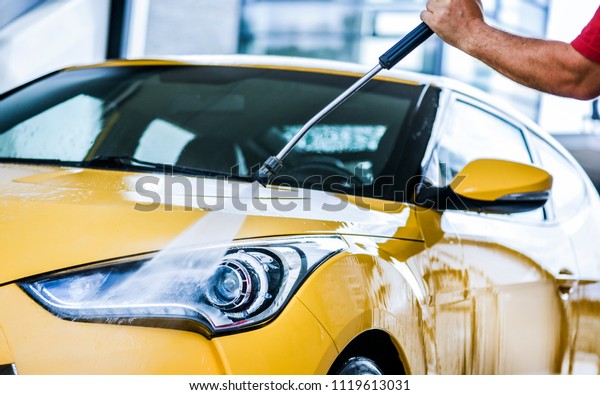 Man cleaning vehicle with high pressure water\
spray or jet. Car wash\
details.