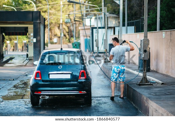 Man\
cleaning vehicle with high pressure water spray or jet. Summer Car\
Washing. Cleaning Car Using High Pressure\
Water
