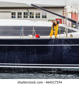 Man cleaning vessel staying in marina. Bergen, Norway.
