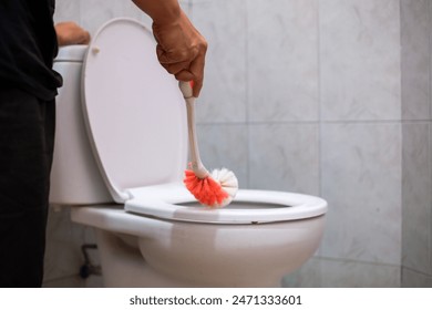 A man cleaning wc. Housekeeper as a cleaning man at the toilet. Brush up Toilet for cleanliness and hygiene. cleaning toilet bowl. Cleaning service concept.