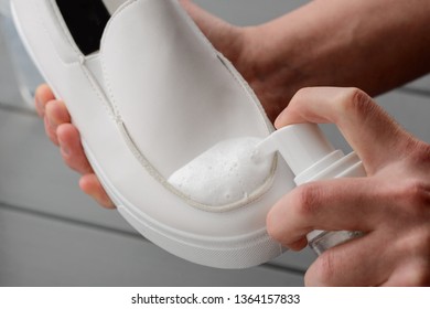 Man Cleaning White Leather Shoes, Close Up On Hands. Usinf A Spray. Proper Care For Footwear To Save A Good Look.