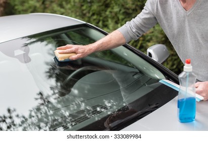 Man Cleaning A Windshield With A Sponge