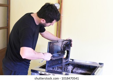 Man Cleaning Wood Burning Stove. Cleaning A Stove For Central Heating