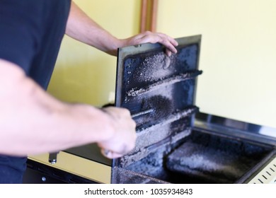 Man Cleaning Wood Burning Stove. Cleaning A Stove For Central Heating