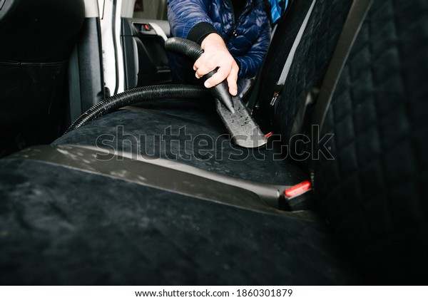Man cleans car interior with vacuum\
cleaner.Cleaning a car using a vacuum\
cleaner
