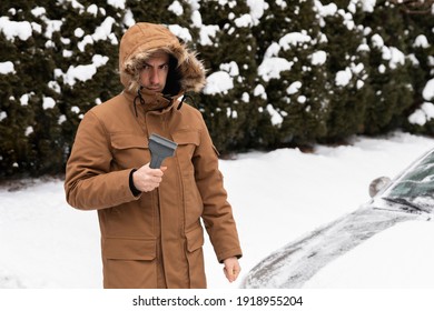 The Man Cleans The Car Of Snow And Ice. The Guy Is Not Happy With The Choice Of Snow Removal Tool.