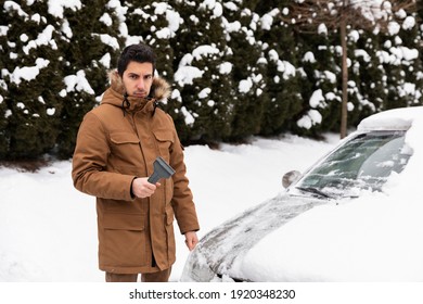 The Man Cleans The Car Of Snow And Ice. The Guy Is Not Happy With The Choice Of Snow Removal Tool.