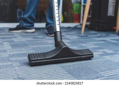 A Man Cleans The Carpet Flooring Of An Office With A Vacuum Cleaner With An Attached Floor Sweeper Nozzle.