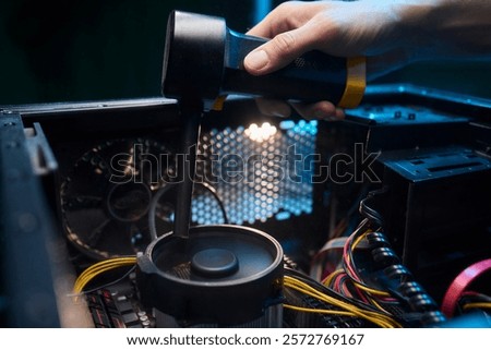A man cleans a computer case with a vacuum in a bright room, stressing workspace tidiness