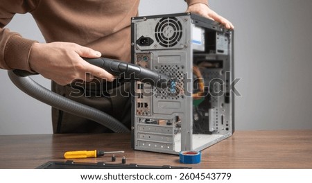 Man cleans a computer case with a vacuum cleaner.