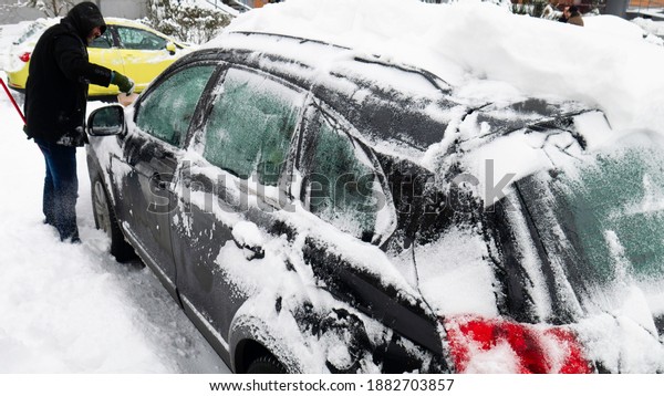 Man\
cleans frozen car covered in snow at winter day.\
