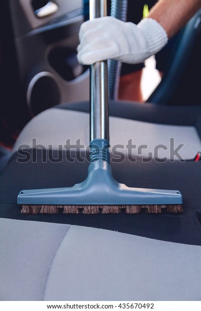 A man cleans the interior of the car. Vacuum
cleaning car seats