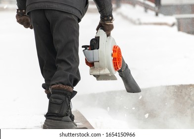 Man cleans pavement from snow with blower - Powered by Shutterstock