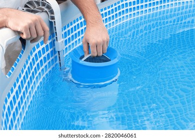 Man cleans skimmer for the frame pool. Contaminated pool cleaning concept.