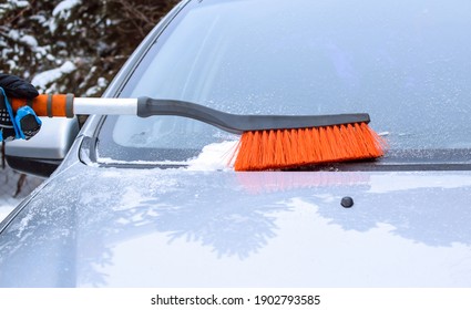 A man cleans snow from a machine with a brush. Snow removal tool. Selective focus.