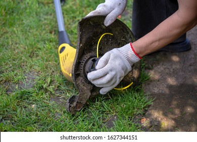 The Man Is Cleansing A Trimmer For Grass Removal. Mowing The Lawn. Repair Of Garden Tools.