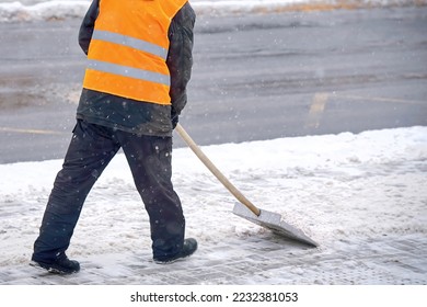 Man clear snow from sidewalk, cleans footpath from snow during blizzard. Utility worker shoveling snow on city street. Janitor clearing snowy walkway with shovel. - Shutterstock ID 2232381053
