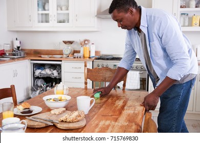 Man Clearing Breakfast Table And Loading Dishwasher