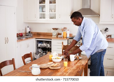 Man Clearing Breakfast Table And Loading Dishwasher