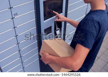 Man client using automated self service post terminal machine or locker to deposit a parcel for storage