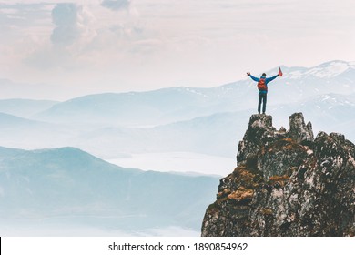 Man climber on mountain cliff summit traveling hike in Norway adventure vacations outdoor extreme activity healthy lifestyle traveler success raised hands Husfjellet peak  - Shutterstock ID 1890854962