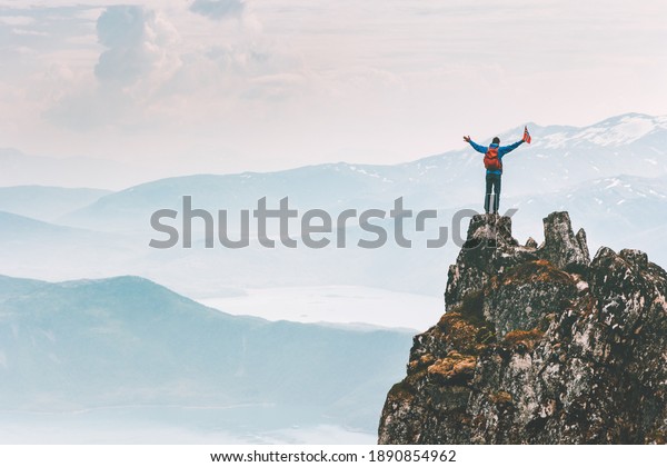 Man climber on\
mountain cliff summit traveling hike in Norway adventure vacations\
outdoor extreme activity healthy lifestyle traveler success raised\
hands Husfjellet peak 