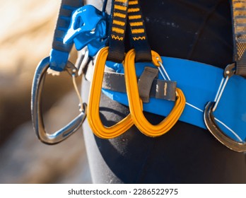 A man and climbing equipment  and easy  clipping carabiners   quick draws  hiker stands against the background mountains    rocks  is engaged in extreme sports   rock climbing 