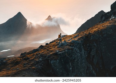 Man climbing mountains traveling in Norway tourist solo hiking in Lofoten islands outdoor traveler with backpack active healthy lifestyle adventure summer vacations  - Powered by Shutterstock