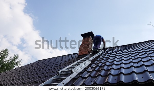 a man climbs a metal ladder to\
the roof of the bathhouse to clean the pipe from soot and\
soot