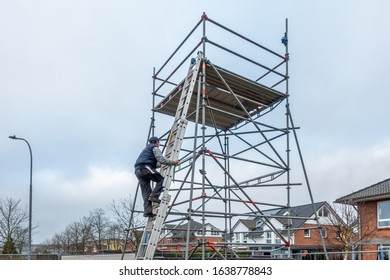 A Man Climbs Onto Scaffolding On An Extension Ladder