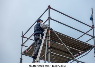 A Man Climbs Onto Scaffolding On An Extension Ladder