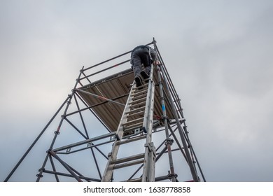 A Man Climbs Onto Scaffolding On An Extension Ladder