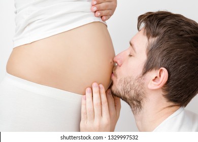 Man with closed eyes kissing pregnant woman naked belly from heart. Emotional loving pregnancy time - 20 weeks. Baby expectation. Happiness and safety concept. Side view. Closeup.