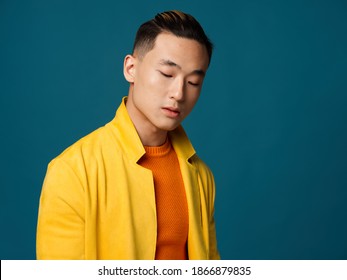 A man with closed eyes in a yellow jacket on a blue background close-up cropped view