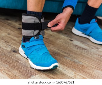 Man Closing Velcro Strap On Ankle Weight During Home Workout