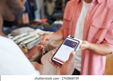 Man In Clothing Store Making Contactless Payment With App On Mobile Phone