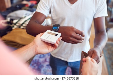 Man In Clothing Store Making Contactless Payment With Smart Watch At Sales Desk - Powered by Shutterstock