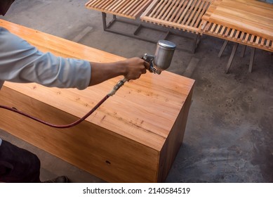 A man coating a cabinet with varnish. At a furniture making shop.