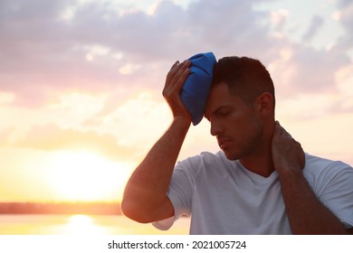 Man With Cold Pack Suffering From Heat Stroke Near River At Sunset