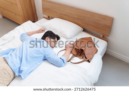 A man collapsing onto the bed from overwork