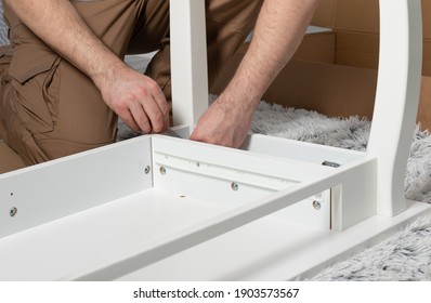 Man Collects White Dressing Table At Home. Furniture Assembly Concept