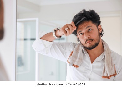 A man combing his hair while looking in the mirror - Powered by Shutterstock