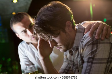 Man comforting his depressed friend in bar - Powered by Shutterstock