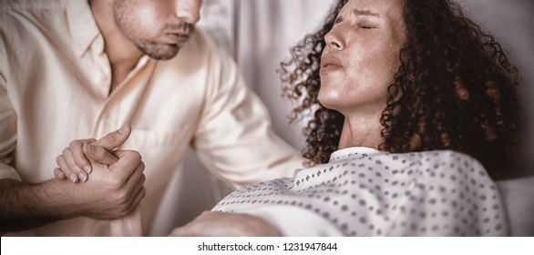 Man Comforting Pregnant Woman During Labor In Ward Of Hospital