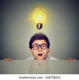 Man Coming Out From Under The Table Looking Up At Bright Light Bulb Above Head 