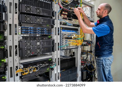 A man commutes wires in a server room. A technician works with server equipment in a data center. - Powered by Shutterstock