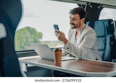 Man commuting by train, looking at smartphone and working on laptop. Blending travel, business, and modern technology