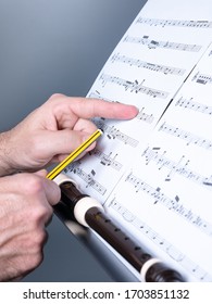 man composing some musical theme and writing on a musical sheet or score, recorder or flute shown, musical education concept