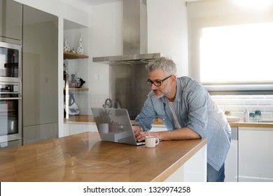 Man with computer at home in modern kitchen - Powered by Shutterstock